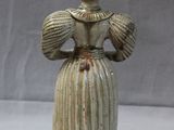 une figurine représentant une femme vêtue d'une robe et d'un chapeau