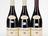 three bottles of red wine sitting next to each other on a table