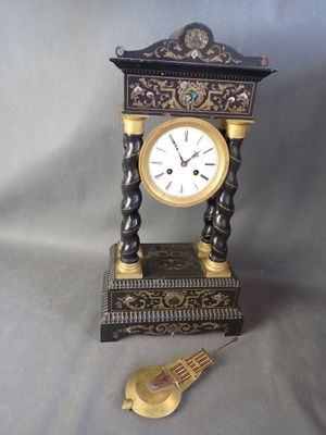 une horloge noire et dorée posée sur une table à côté d'une horloge dorée