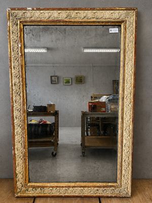 un miroir ancien dans un cadre doré posé sur un parquet, dans une pièce