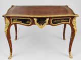 an antique writing table with a gold leaf decoration and a brown leather top