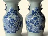 une paire de vases bleus et blancs ornés de fleurs, posés sur un fond blanc