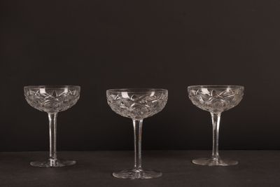 trois verres à vin vides posés sur une table, sur fond noir