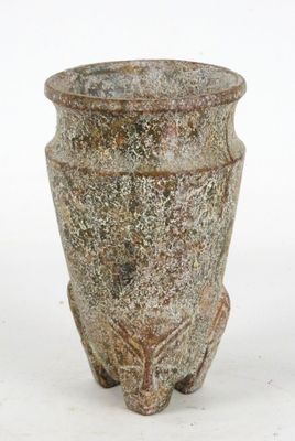 un petit vase posé sur une surface blanche