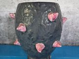 a black vase with pink flowers on it on a blue table