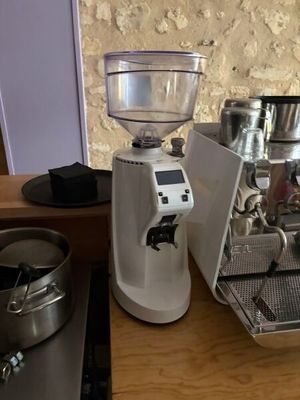 un moulin à café posé sur un plan de travail, à côté d'une cafetière