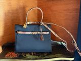 blue leather handbag with snake skin strap on top of a book