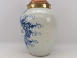 a white and blue vase with a gold lid
