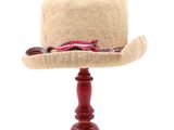 un chapeau posé sur un support, sur une table blanche