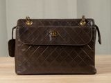 brown chanel bag sitting on a table with a curtain in the background