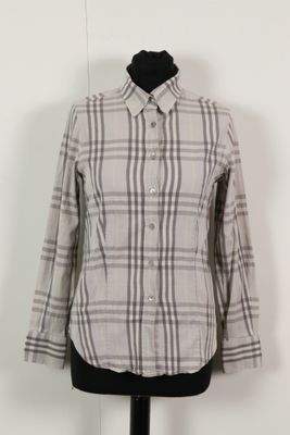 La chemise est posée sur un mannequin devant un mur blanc.