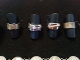 several different rings and bracelets are displayed on a black surface
