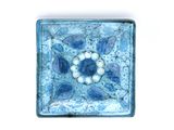 a blue and white tile with a flower design on it