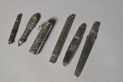 quatre types de couteaux différents et un stylo posés sur une surface blanche