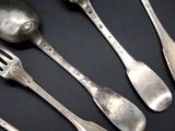 five spoons and a fork on a black table