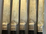 six knives are lined up on a table next to each other