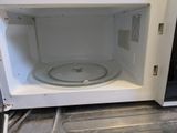 a white microwave with the door open on the stove