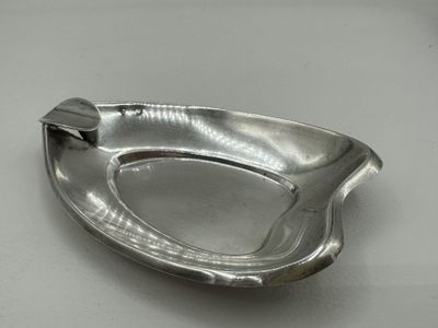 a silver ashtray on a table with a spoon in it