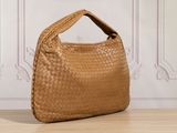 the large tan woven bag is sitting on a wooden table