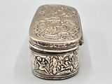 an antique silver box with a floral design on the lid