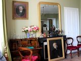 une photo d'un salon avec le portrait d'un homme accroché au mur
