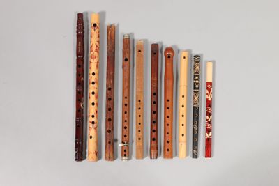 five wooden flutes lined up in a row on a white surface