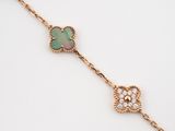 a close up of a gold bracelet with a green and white flower