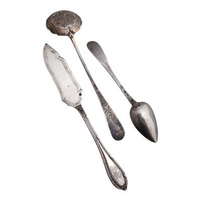 deux cuillères et une fourchette en argent sur une surface blanche
