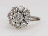 a close up of a diamond cluster ring on a white surface