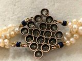 a close up of a necklace with pearls and a broochet