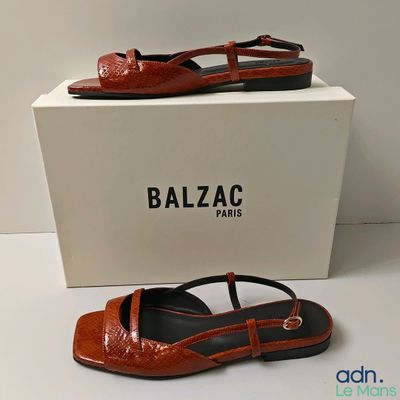 Chaussures Balzac orange et noires, avec une boîte posée sur un fond blanc