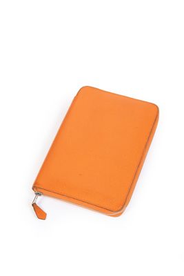 un carnet en cuir orange muni d'une fermeture à glissière, sur fond blanc