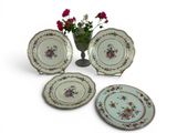 four plates and a vase of flowers sit on a white surface