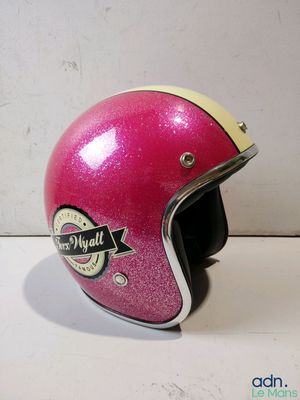 pink motorcycle helmet with a sticker on it sitting on a table