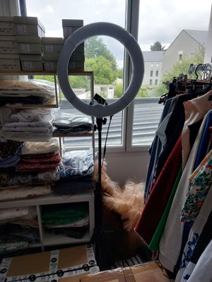 a photo of a room with a lot of clothes and a ring light