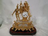 une horloge en or avec une statue d'un homme et d'une femme dessus