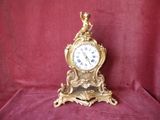 a gold clock with a bird on top of it