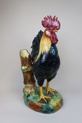 a figurine of a rooster standing on a tree branch