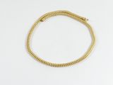 un bracelet plaqué or orné d'un motif en spirale sur fond blanc