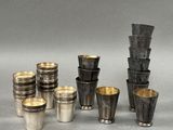 Plusieurs coupes et tasses en argent sont alignées sur une surface grise