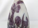 a white vase with purple flowers on it sitting on a table