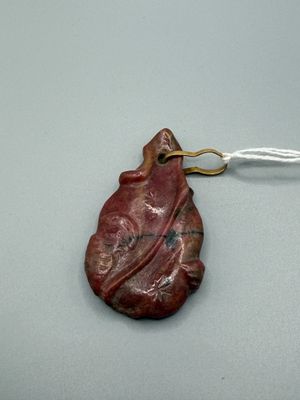 une photo d'un pendentif rouge en forme de feuille, suspendu à un cordon blanc