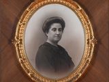 an old photo of a woman in a black dress in a gold frame