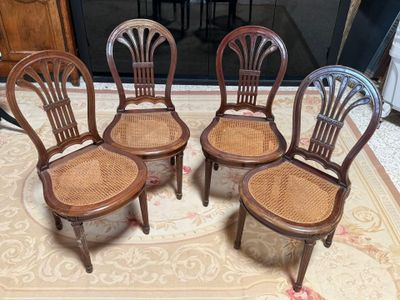 four wooden chairs sitting on top of a rug in a living room