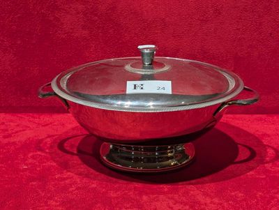 un grand pot en argent muni d'un couvercle, posé sur un support rouge