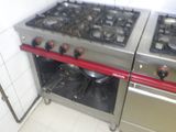 deux cuisinières qui se trouvent dans une cuisine équipée de poignées rouges