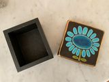a black box with a blue flower on it next to a black box with a blue flower on it