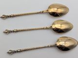 three antique spoons are sitting on a white surface