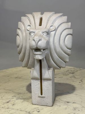 sculpture représentant une tête de lion avec un cure-dent qui dépasse de sa gueule