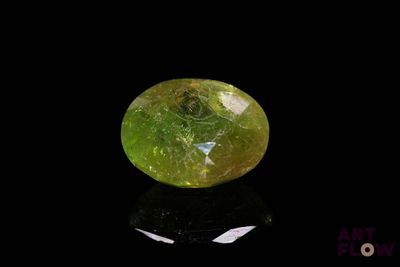 a close up of a yellow and green diamond on a black surface